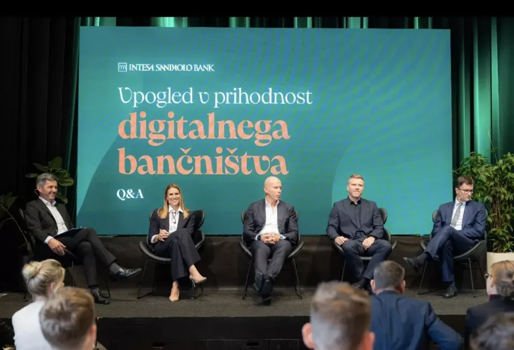Panelna razprava na odru pred zaslonom Intesa Sanpaolo Bank na predstavitvenem dogodku.